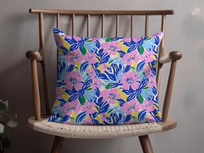 Pink and blue floral pattern on a throw pillow on a wooden chair.