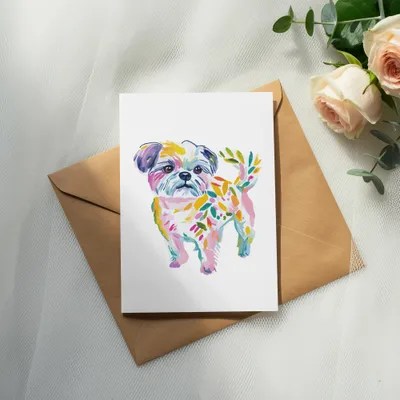 Watercolor shih tzu with colorful floral accents on a white card above an envelope.
