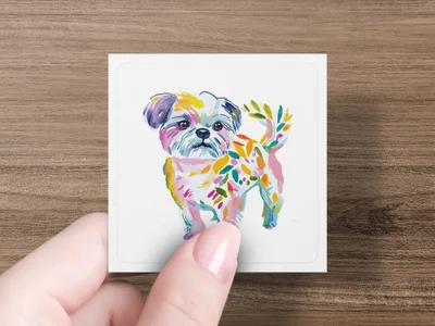 Hand holding square card featuring colorful painted dog with leaf-like accents.
