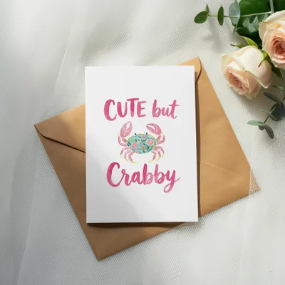 Card with "Cute but Crabby" text and pink crab illustration on brown envelope.
