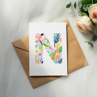 Watercolor letter N with colorful floral design on card and envelope.