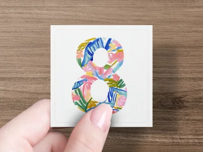Hand holding card with colorful floral patterned number 8.