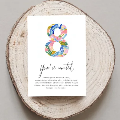 Card with "You're invited" and floral "8" on wood slice.