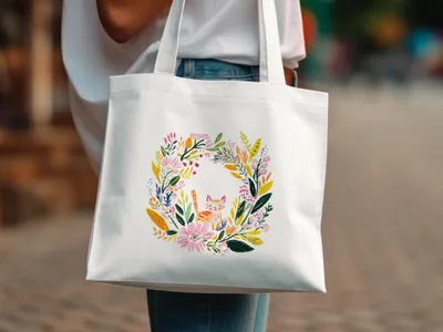 White tote bag with a floral wreath and a cat in the center.