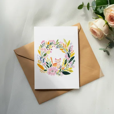 Greeting card with floral wreath and cat illustration on a brown envelope.