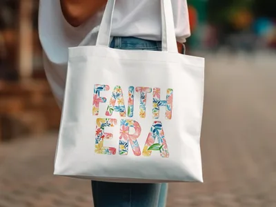 White canvas tote bag with "FAITH ERA" in floral lettering.