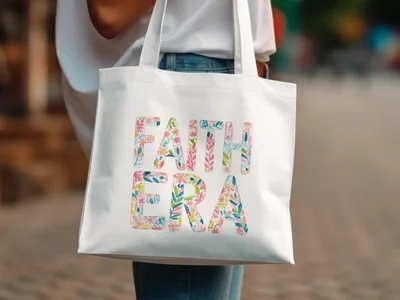 White canvas tote bag with "FAITH ERA" in floral letter design.