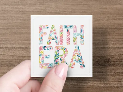 Card with "FAITH ERA" in floral letters held by fingers.