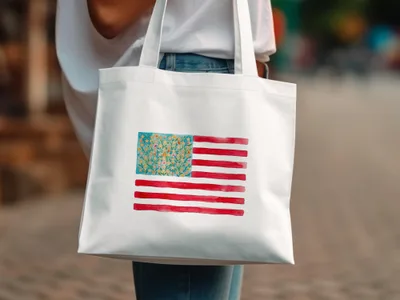 White tote bag with watercolor American flag design featuring floral accents.