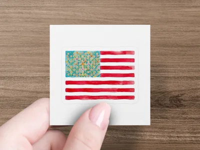 Hand holding an American flag sticker with floral stars.