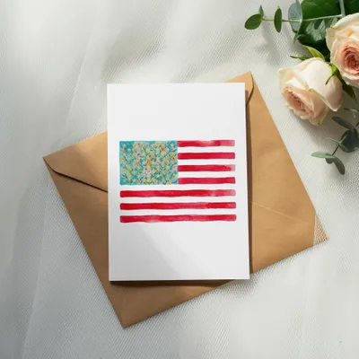Watercolor American flag card with floral accents on a kraft envelope.
