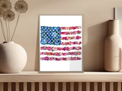 Floral American flag art in a white frame on a shelf.