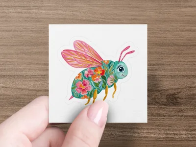 Whimsical bee sticker with floral wings and body on a white background.