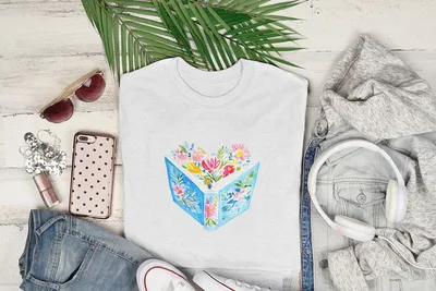 White t-shirt with open book and colorful flowers design.