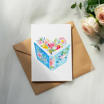 Watercolor illustration of an open book with flowers spilling out, on a brown envelope.