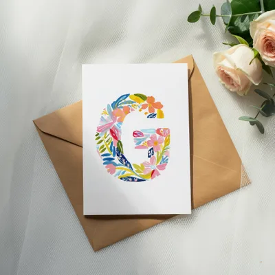 Card with a floral letter G on a brown envelope.