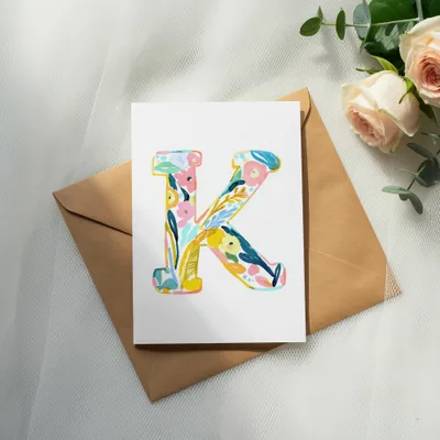 Floral letter K on card with envelope and roses.