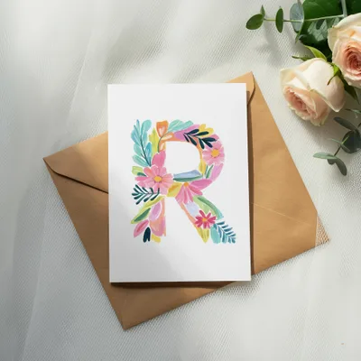 Watercolor letter R with floral accents on a card and envelope.