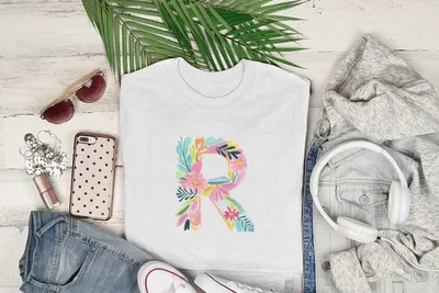 White t-shirt with large colorful floral letter "R" graphic.