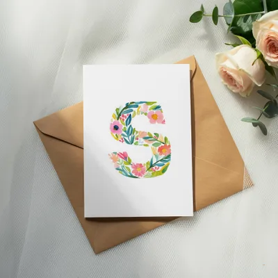Card with floral letter S on brown envelope, with roses and eucalyptus.