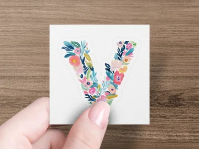 Hand holding letter "V" with a floral watercolor design.