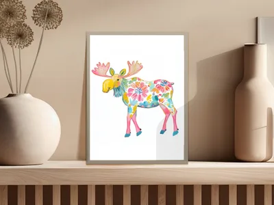 Colorful floral moose artwork in a frame on a shelf.