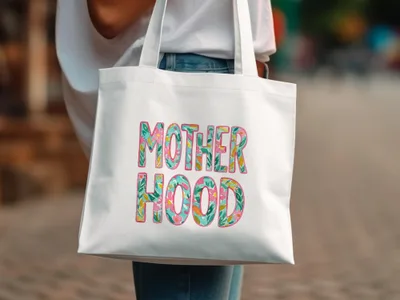 White tote bag with "Motherhood" in colorful floral letters.