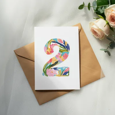 Card with colorful floral "2" on brown envelope, with roses and eucalyptus.