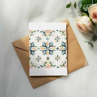 Card with floral pattern on a brown envelope, next to roses and eucalyptus.