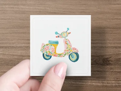 Pink floral patterned scooter illustration on a white card held by a hand.