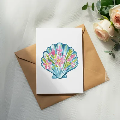 Watercolor illustration of a blue seashell filled with pink and green flowers on white card.