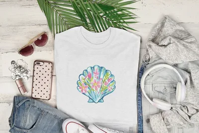 White t-shirt with a watercolor seashell and flower design.
