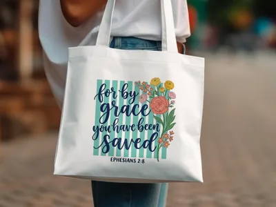 White canvas tote bag with floral design and "for by grace you have been saved Ephesians 2:8".