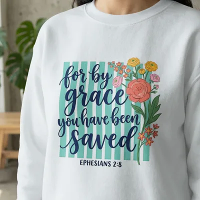 White sweatshirt with "for by grace you have been saved" in blue script and Ephesians 2:8.