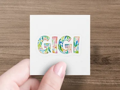 Gigi text with colorful floral watercolor pattern held by a hand.
