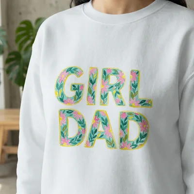 White sweatshirt with "GIRL DAD" in floral lettering.
