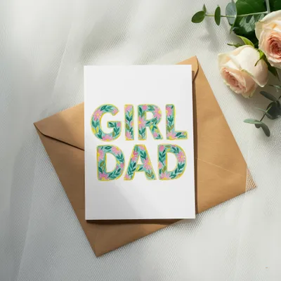 Greeting card with "Girl Dad" text in floral letters on an envelope.