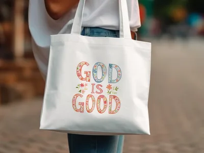 White tote bag with "God is Good" text in floral lettering.