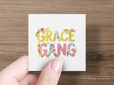 Square sticker with "GRACE GANG" in colorful, floral lettering held by a hand.