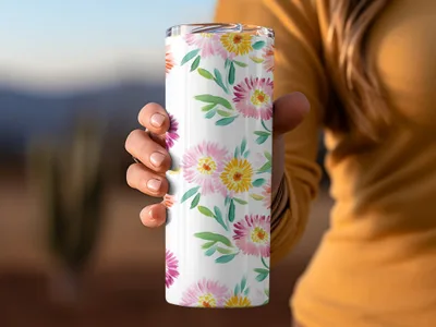 White tumbler with colorful floral watercolor pattern held by a hand.