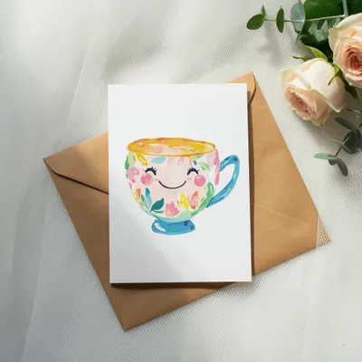 Hand-painted smiling teacup with colorful floral designs on card.