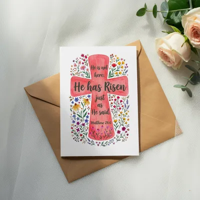 Cross with "He has Risen" text and floral details on card, with envelope.