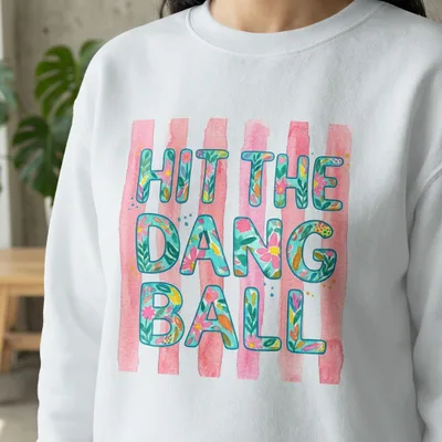 White sweatshirt with "Hit the dang ball" in floral watercolor letters.