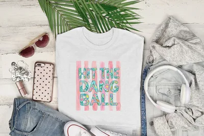 White t-shirt with "HIT THE DANG BALL" text on pink and white stripes.