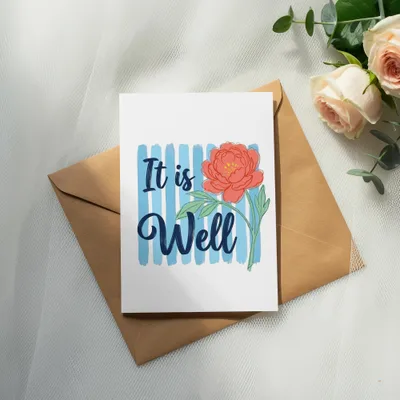 Card with "It is Well" text and coral peony on striped background, on envelope.