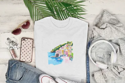 White t-shirt with colorful coastal town graphic, styled with denim and headphones.