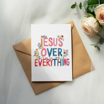 Card with "Jesus Over Everything" text and colorful flowers, on an envelope.
