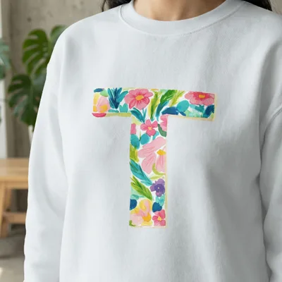 White sweatshirt with a large floral letter "T" design.