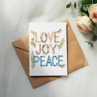 Greeting card with "LOVE JOY PEACE" in colorful, floral lettering on envelope.