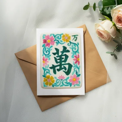 Card with green Chinese character "wan" and floral design on envelope.